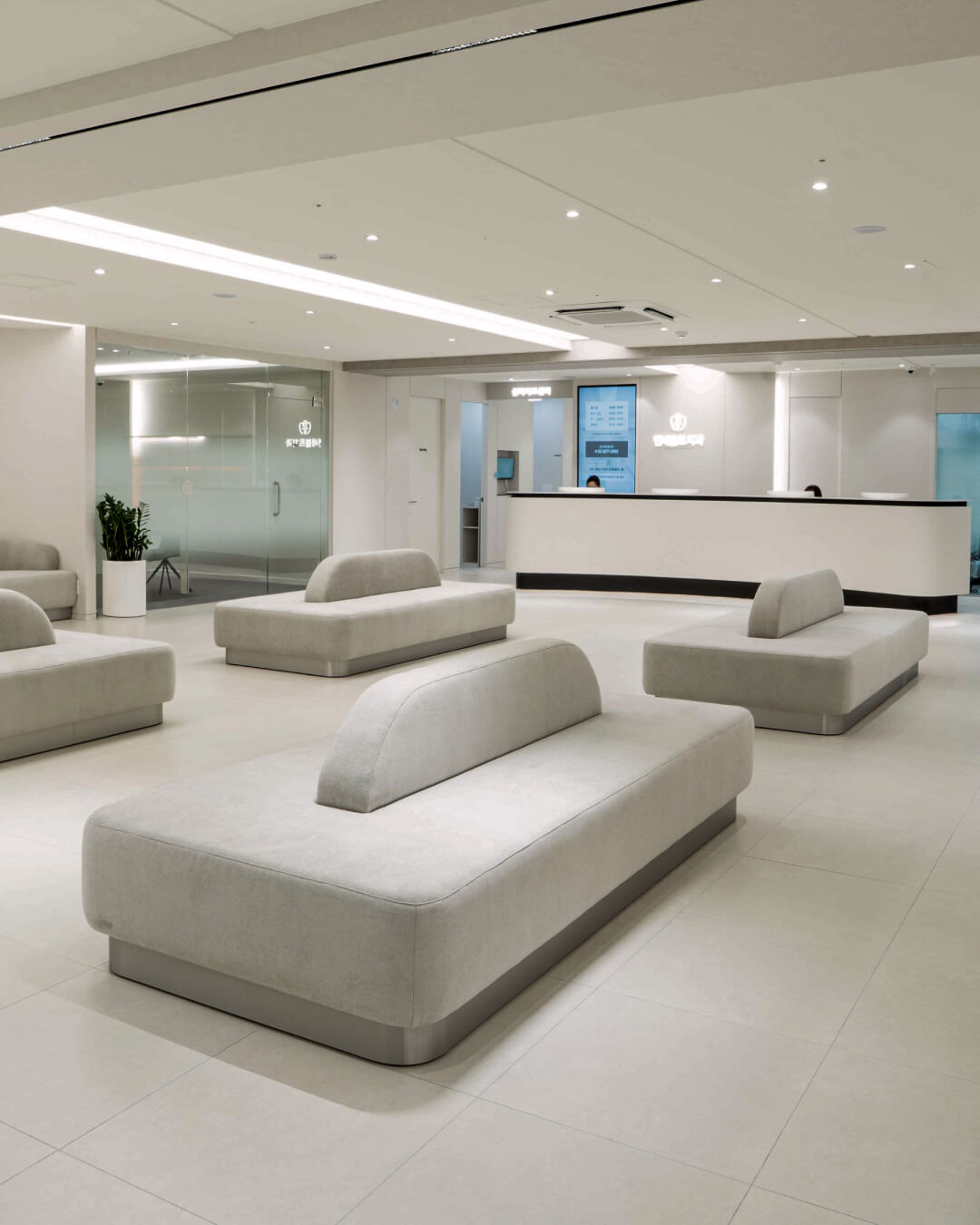 A modern lobby of yonsei bolt dental clinic in Yeongdeungpo, seoul, with several light gray upholstered lounge chairs arranged around a reception desk in a bright, minimalist interior.